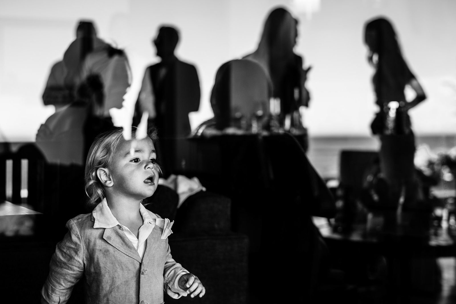 Boy looking up at a wedding reception by the sea, black and white — documentary wedding photography in Mexico by Dennis Berti